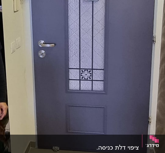 אדם עומד ליד דלת מצופה עם עיצוב זכוכית